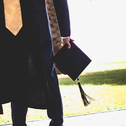 A student holding a graduation hat.