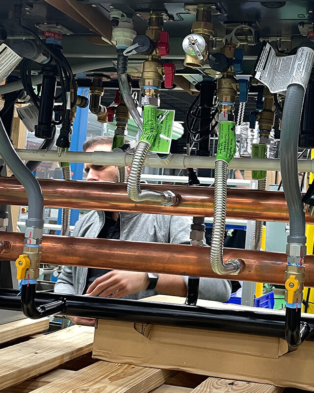 A person working at a desk, writing. The desk contains various engineering diagrams and notes.