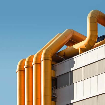 Corner view of a roof with large yellow pipes sticking out.